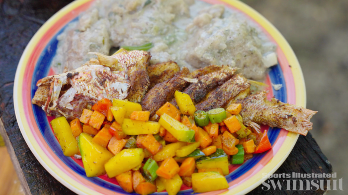 A finished plate of Hudut, sautéed vegetables, and fried fish.